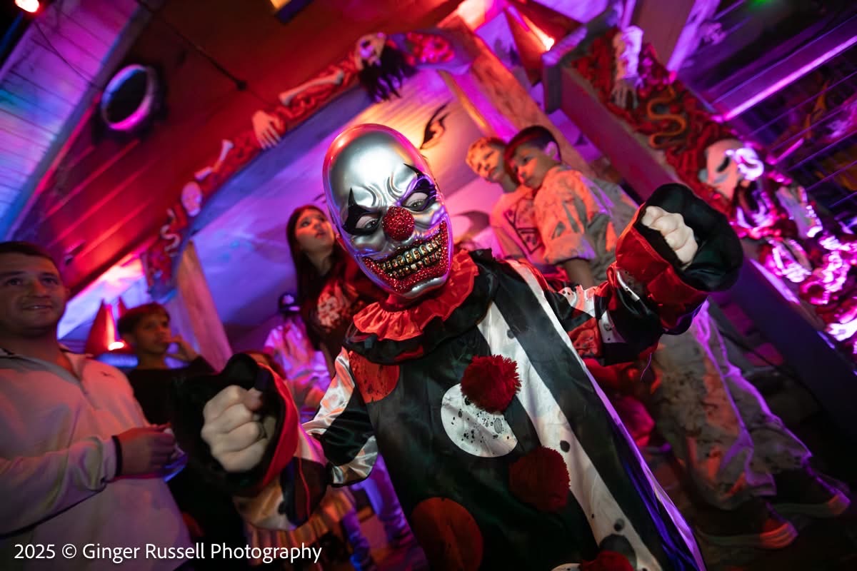 A costumed clown character posing with visitors inside the haunted house