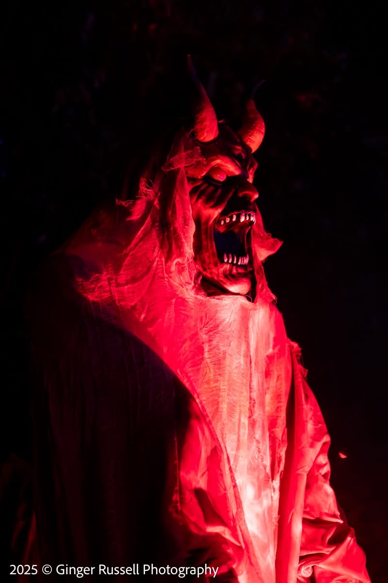 A close-up portrait of a red-lit devil mask character