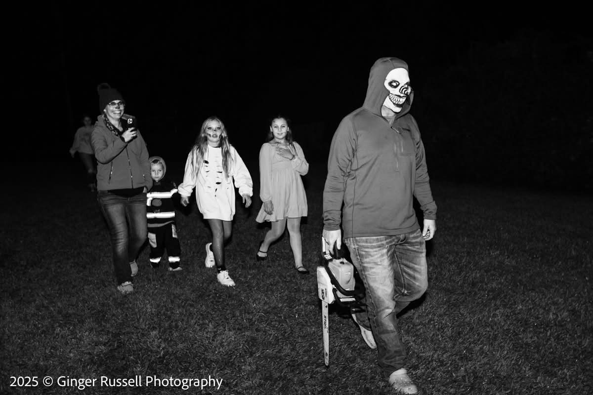 Black and white photo of a family walking through the haunted house grounds at night