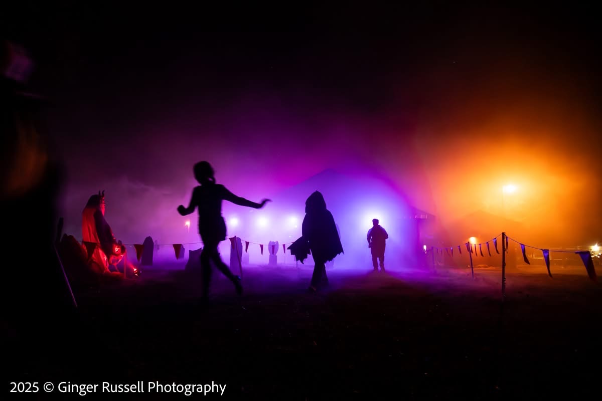 Silhouetted figures walking through purple and pink fog at night