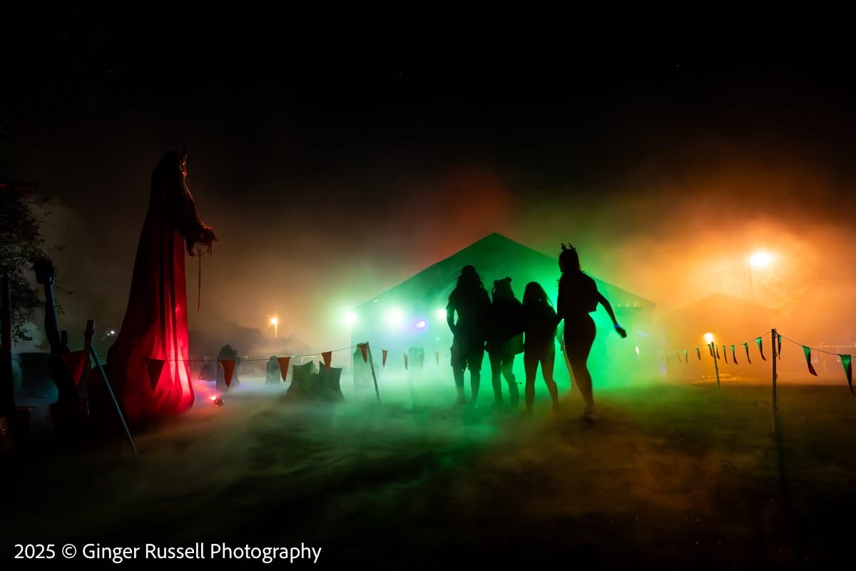 A robed figure leading a silhouetted group through green fog at night